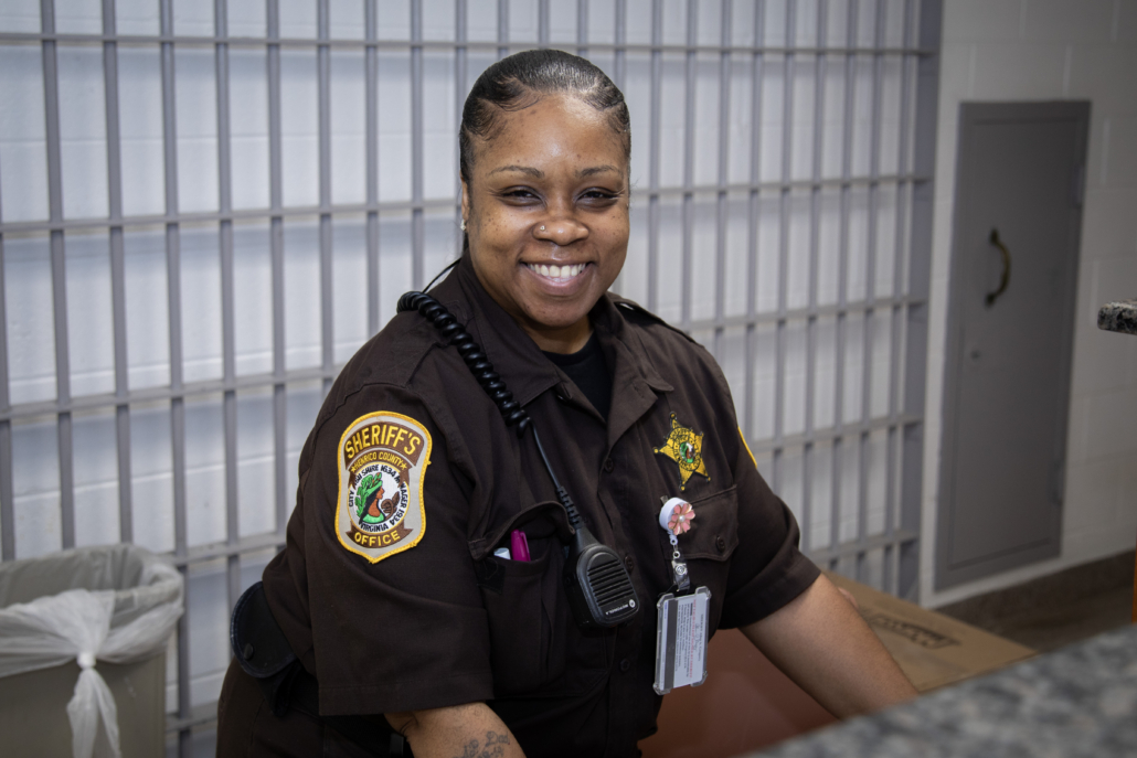 Sheriff's officer jailor working at a counter in a jail smiling